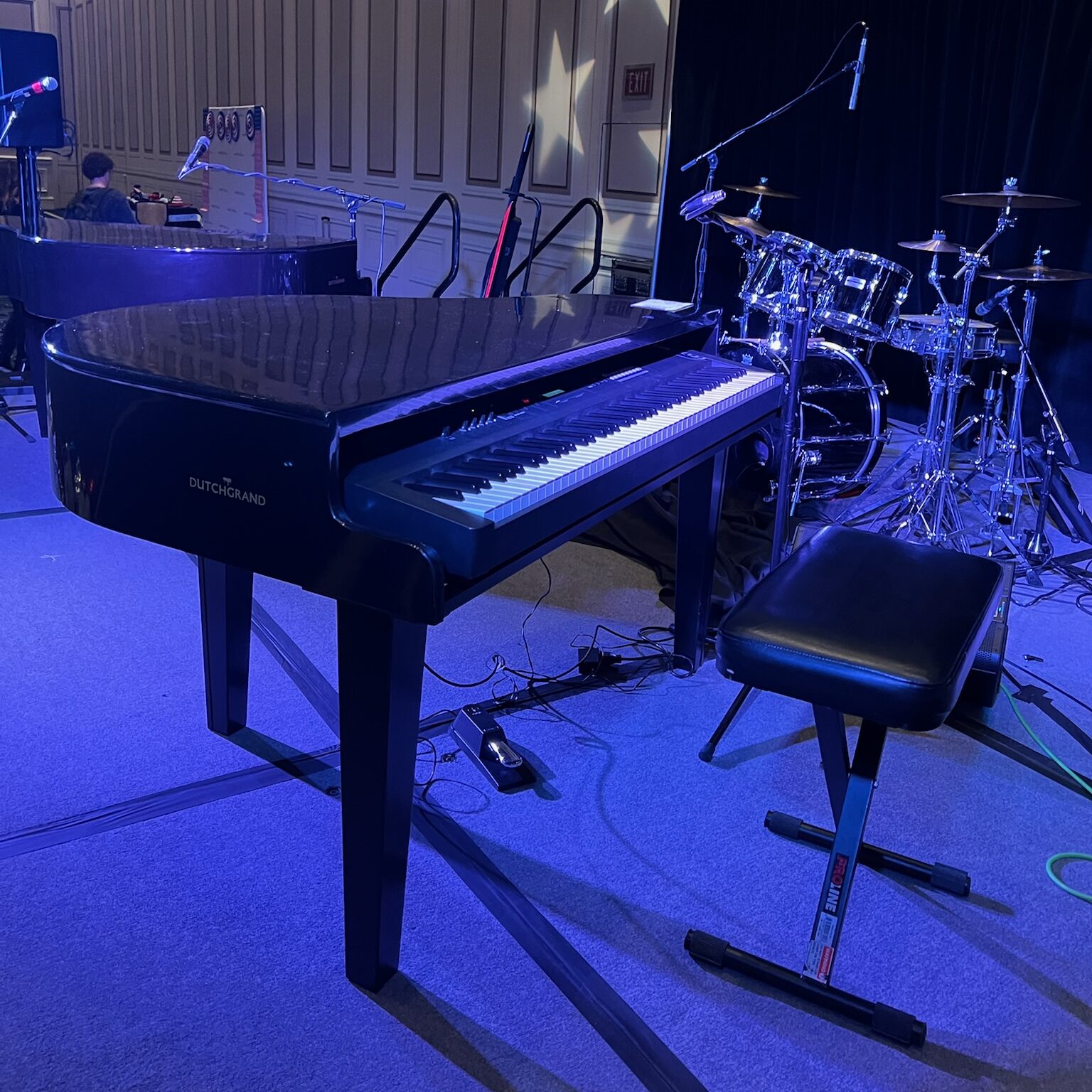 Black piano shell, keyboard, and bench on a stage